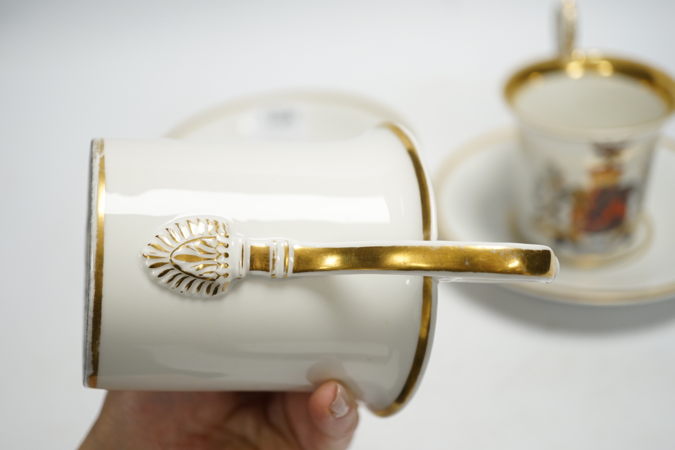 A pair of German porcelain armorial cups and saucers, one saucer reads ‘Lord Bingham s/m Y. Powell. Born 1848’